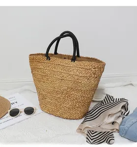 Close-up of handmade straw tote bag with black woven handles and magnetic clasp