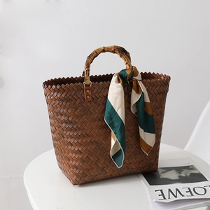 Brown woven straw tote bag with natural bamboo handles and a green striped silk scarf
