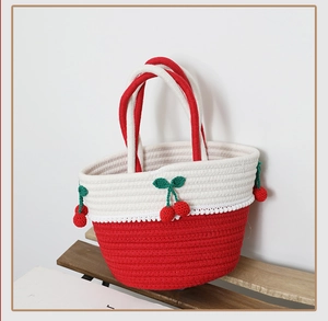 Close-up of handmade red and white cotton woven bag with 3D knitted cherry charms