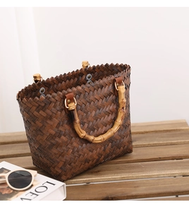 Detail of hand-woven dark brown tote bag featuring natural bamboo handles and metal rings