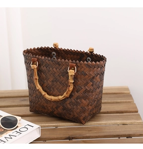 Detail of dark brown woven straw bag with natural bamboo handles and textured finish
