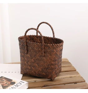 Detailed close-up of dark brown woven straw bag with ring handles and jagged edge design