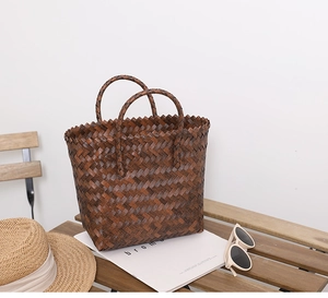 Detailed herringbone texture of dark brown woven straw tote bag for summer beach