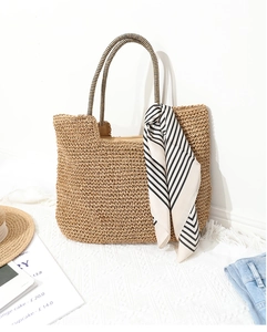 Detail of hand-woven straw tote bag with striped scarf and refined crochet texture
