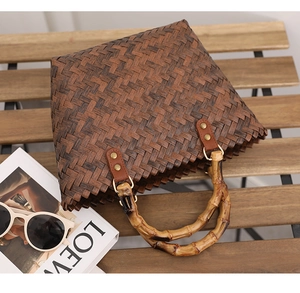 Detail of dark brown woven tote bag featuring retro bamboo handles and square texture