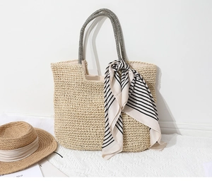 Detail of woven straw tote bag with black and white striped silk scarf decoration