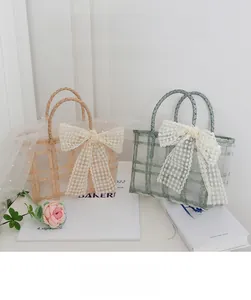 Detailed view of translucent woven tote bags with large lace bows in beige and sage green