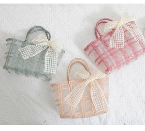 Three colorful woven bridesmaid gift baskets with large lace bows on a white fabric surface