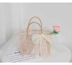 Detail of woven straw bridesmaid bag with lace bow, pink crochet rose and pearl mesh
