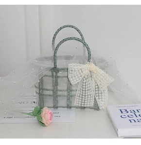 Detail of mint green woven handbag with white lace bow and pearl mesh decoration