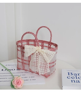 Detail of pink and white woven basket bag with a lace bow and rustic decorative props