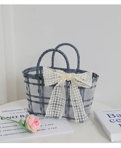 Close-up of blue and white checkered woven handbag with a decorative lace bow detail