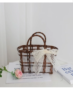 Close-up of a woven tote bag with a lace bow and plaid pattern on a white table