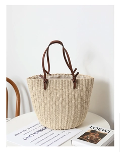 Detailed texture of hand-woven beige straw bucket bag with elegant brown leather handles