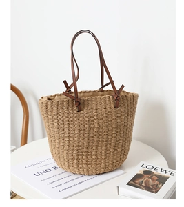 Close-up of woven straw tote bag texture with brown leather handles on a white table