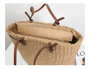 Detail view of woven straw bucket bag showing interior lining and secure zipper closure