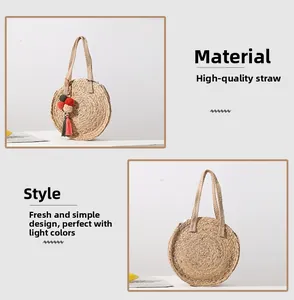 Detail of round straw bag made of natural grass with colorful pompom charms and long straps