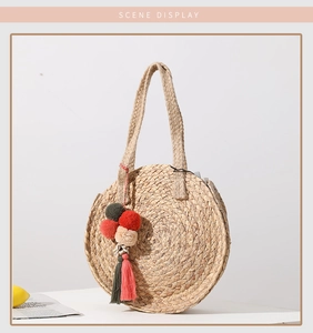 Detail of round straw bag with colorful pom-pom charms and bohemian tassel accents