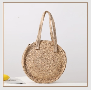 Detailed view of handmade circular straw shoulder bag with woven texture and handle