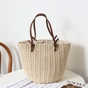 Handwoven straw tote bag with brown leather shoulder straps for casual summer beach look