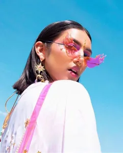 Detail of pink flame rimless sunglasses with jagged edges and stylish golden star earrings
