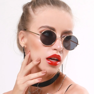 Retro small round metal sunglasses with gold frames and dark lenses on a fashion model