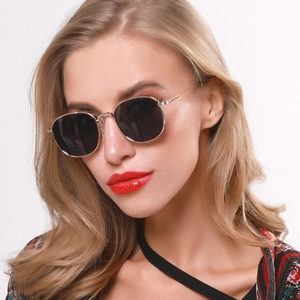 Close-up of stylish black oval lenses with thin gold metal frames worn by a fashion model