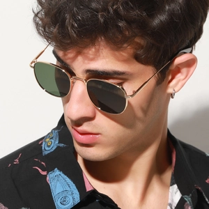 Close-up of retro square metal sunglasses with gold frames and dark lenses on a model