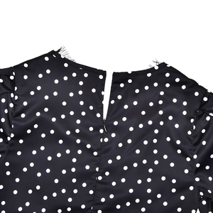 Detailed view of polka dot dress featuring raw edge neckline and hidden back zipper