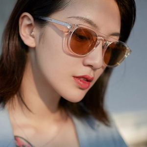 Retro pilot sunglasses with transparent frames and orange lenses worn by a female model