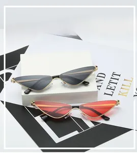 Détail de lunettes de soleil œil-de-chat triangulaires à verres gris et orange sur décor