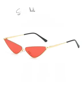 Détail de lunettes de soleil œil de chat triangulaires avec verres rouges et métal doré