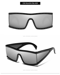 Detail of oversized flat top sunglasses with silver mirror lenses and studded punk frame