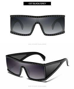 Detail of black oversized square sunglasses featuring silver punk studs and gradient lenses