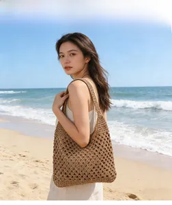 Détail du sac à bandoulière en paille crocheté montrant la texture tissée à la plage