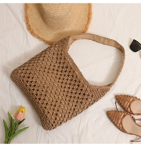 Gros plan détaillé du sac cabas en paille tissée marron sur tissu blanc texturé