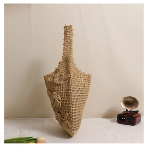Nahaufnahme der hohlen Stroh-Schultertasche mit 3D-Blumenakzenten und gewebter Netzstruktur