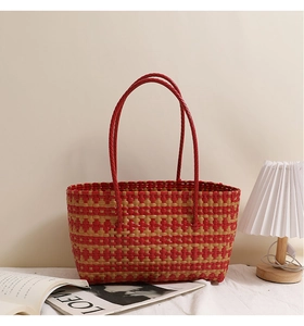 Detail of red and beige checkered woven tote bag with slim handles in a lifestyle setting