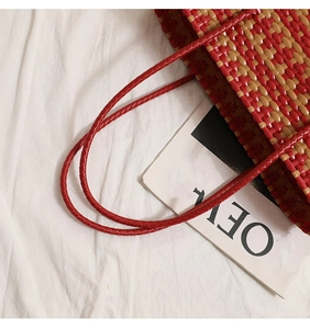 Detail of red and beige woven tote bag with square pattern and top handles