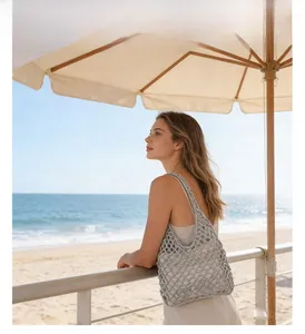 Detail of silver hollow straw shoulder bag with inner pouch on a beach background