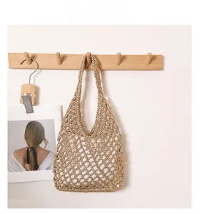 Close-up of golden woven mesh straw bag hanging on a wooden hook in a minimalist setting