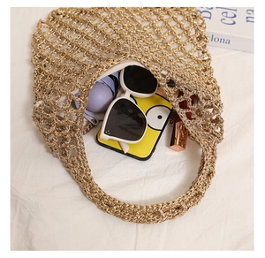 Detailed close-up of metallic gold woven beach bag with hollow mesh and personal items