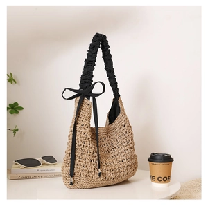 Détail du sac à bandoulière en paille tressé avec bandoulière à volants et nœud noir