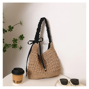 Détail du sac cabas en paille tressée avec bandoulière plissée noire et ruban à nœud