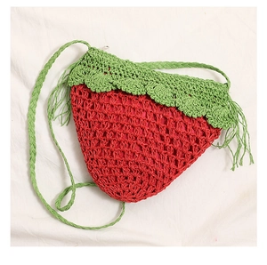 Close-up of strawberry crochet bag featuring red hollow mesh and green leaf lid detail