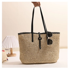 Detailaufnahme der gewebten Strohtasche mit schwarzen Lederriemen und Schnallenakzent