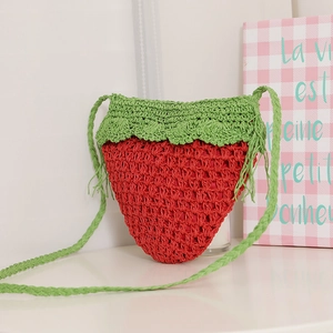 Handwoven strawberry straw crossbody bag with green leaf detail and braided shoulder strap