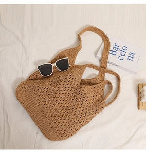 Detail of hollow woven cotton mesh and brown shoulder strap on a large beach tote bag