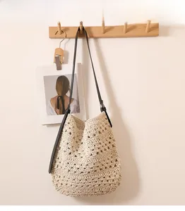 Détail du sac bandoulière au crochet crème avec motifs ajourés et bandoulière en cuir noir