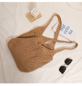 Close-up of brown hollow crochet knit bag on white fabric with casual props